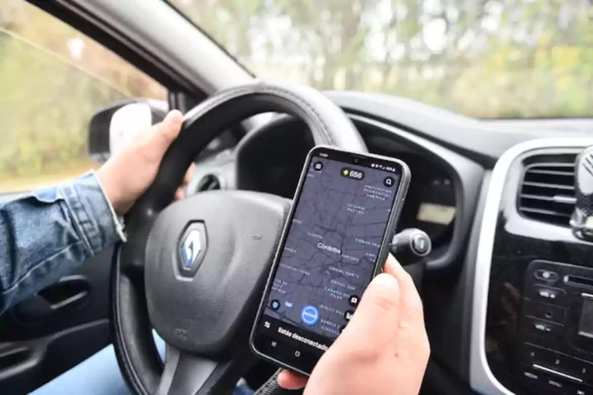 Person driving a Renault car while holding a mobile phone with a maps app open Person driving a Renault car while holding a mobile phone with a maps app open