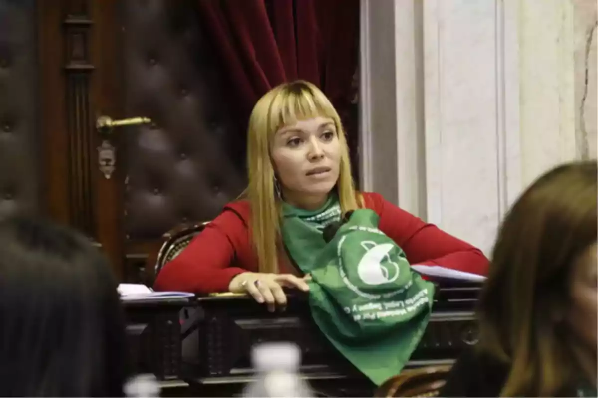 Woman sitting at a desk with a green scarf resting on the table in an institutional setting Woman sitting at a desk with a green scarf resting on the table in an institutional setting