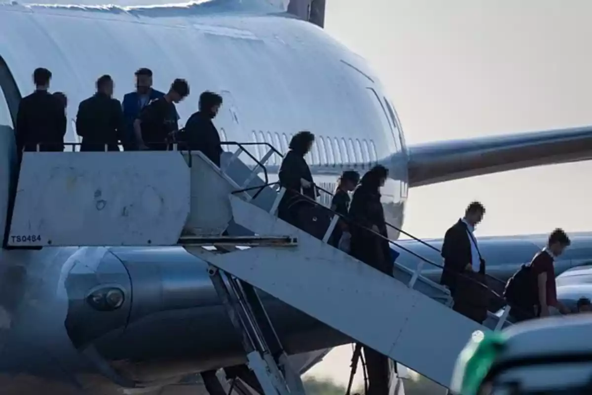 Personas descendiendo por una escalera desde un avión estacionado en la pista