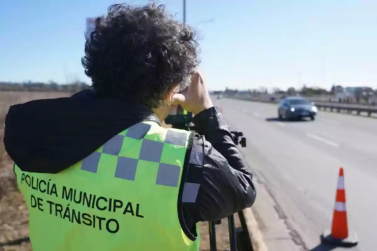 Municipal traffic officer using a speed radar on a road next to an orange cone