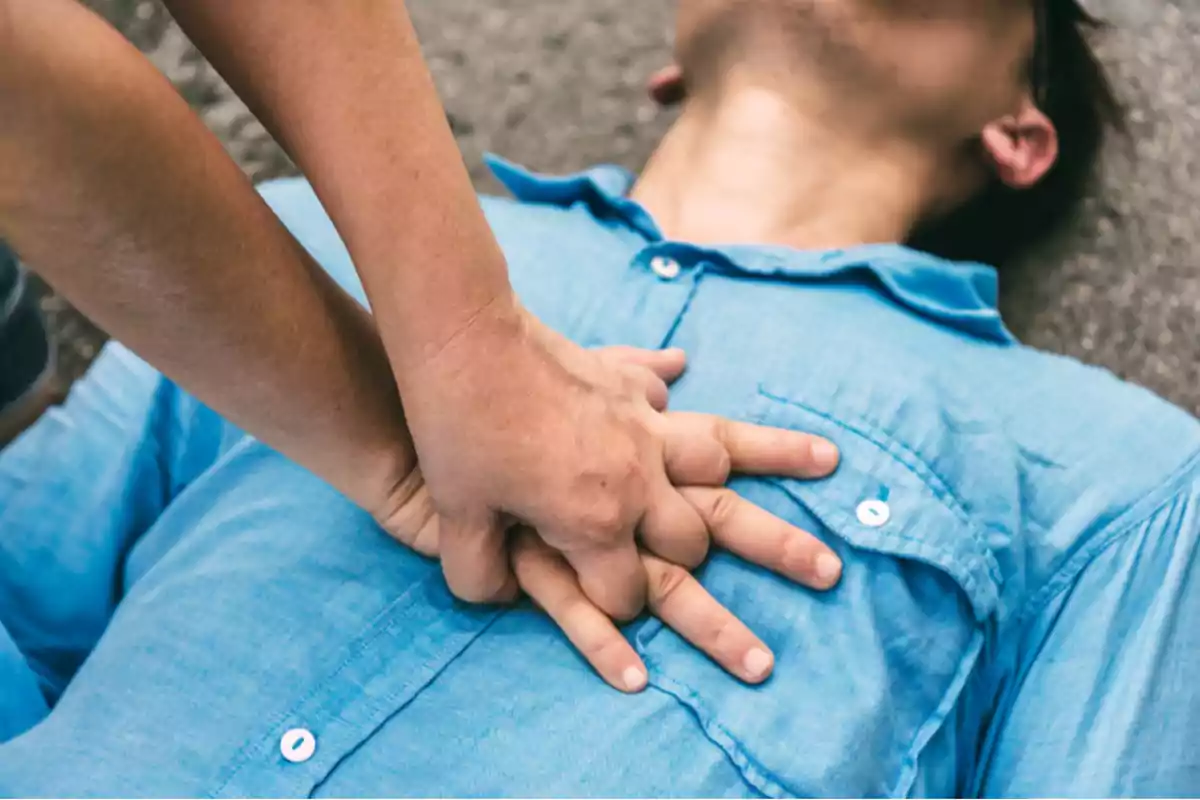 Person performing cardiopulmonary resuscitation maneuvers on a man lying on the ground Person performing cardiopulmonary resuscitation maneuvers on a man lying on the ground