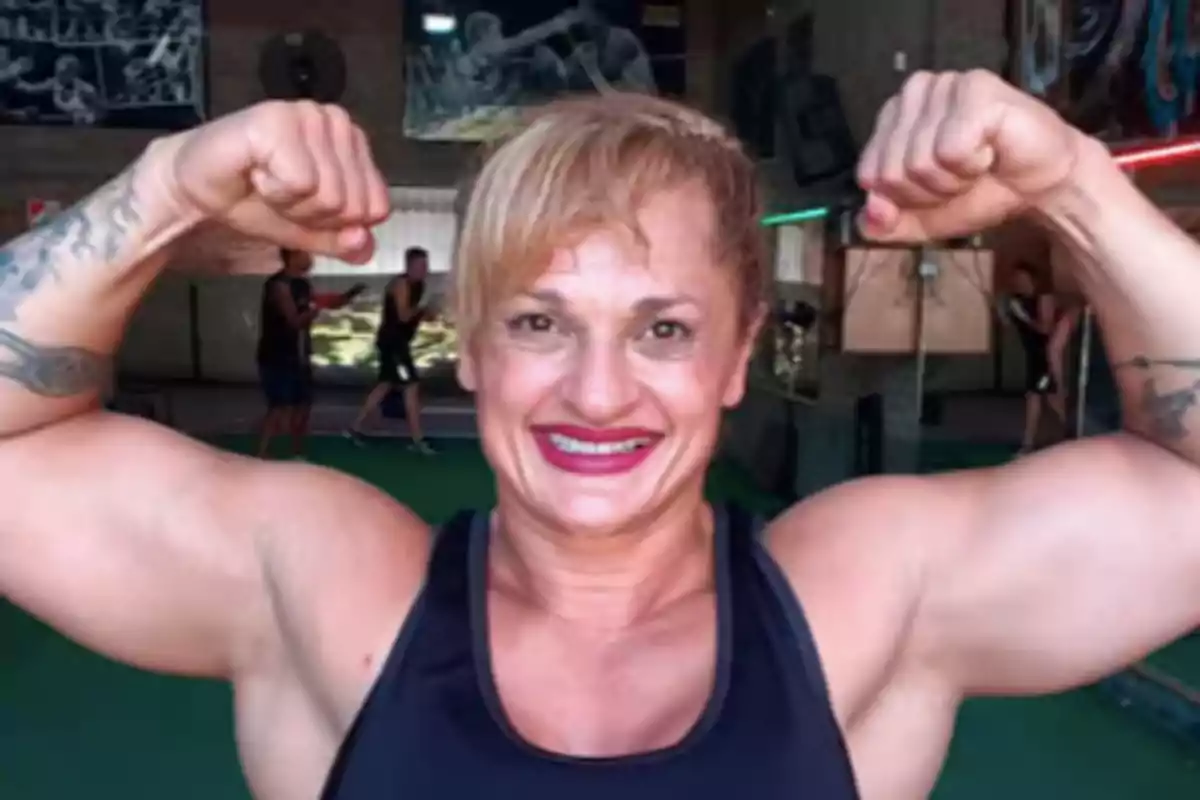 Smiling woman showing off her muscles in a gym