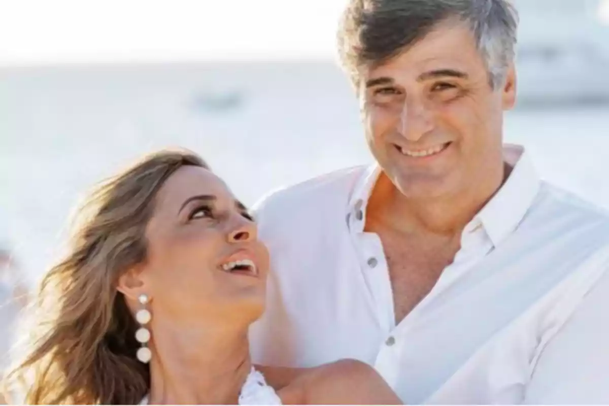 Smiling couple dressed in white enjoying a moment together on the beach