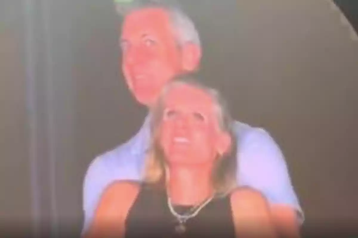 Una pareja sonríe mientras posa abrazada en un ambiente oscuro Una pareja sonríe mientras posa abrazada en un ambiente oscuro