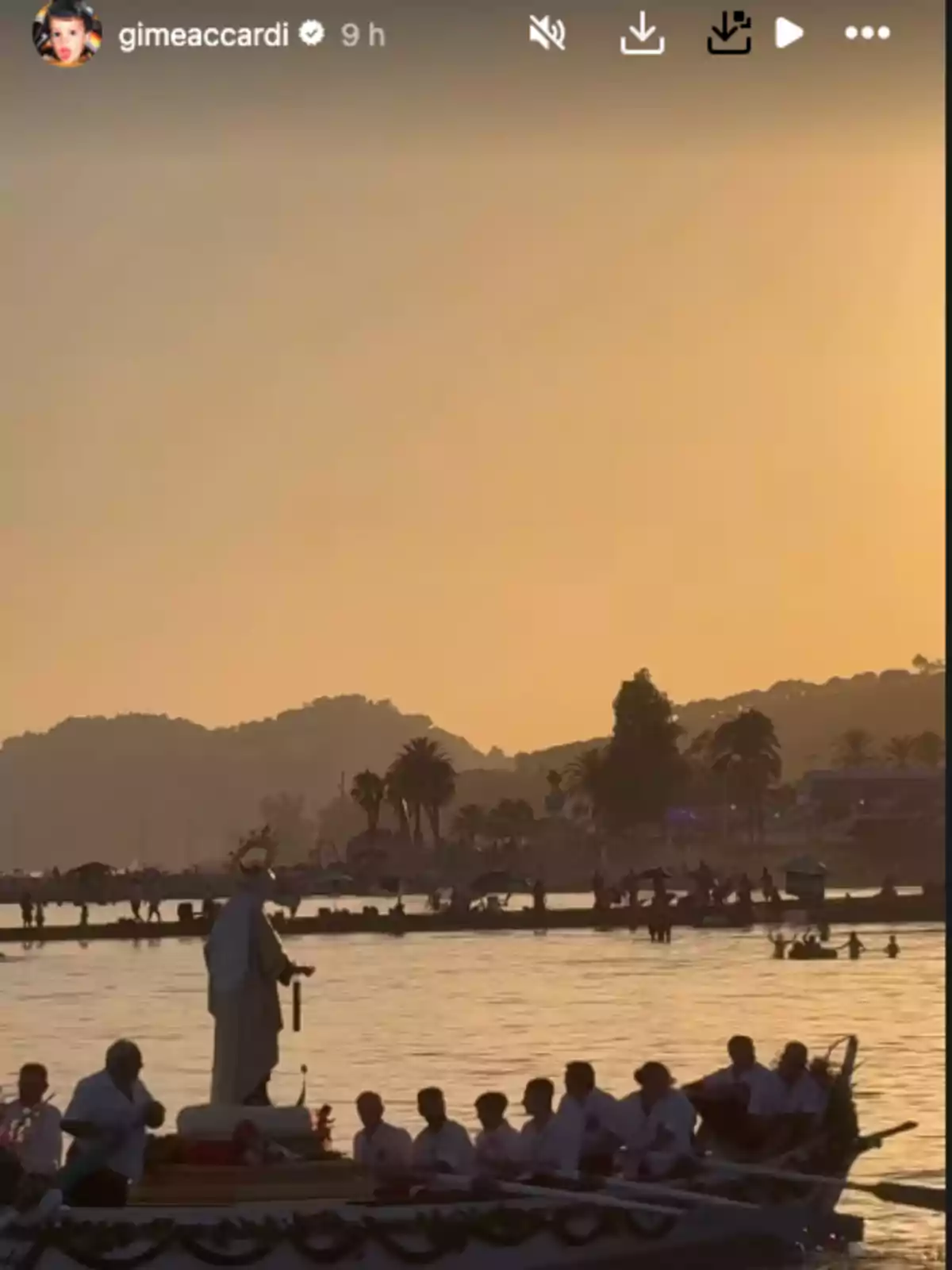 People rowing a boat carrying a religious statue at sunset on the beach, with palm trees and people in the background People rowing a boat carrying a religious statue at sunset on the beach, with palm trees and people in the background
