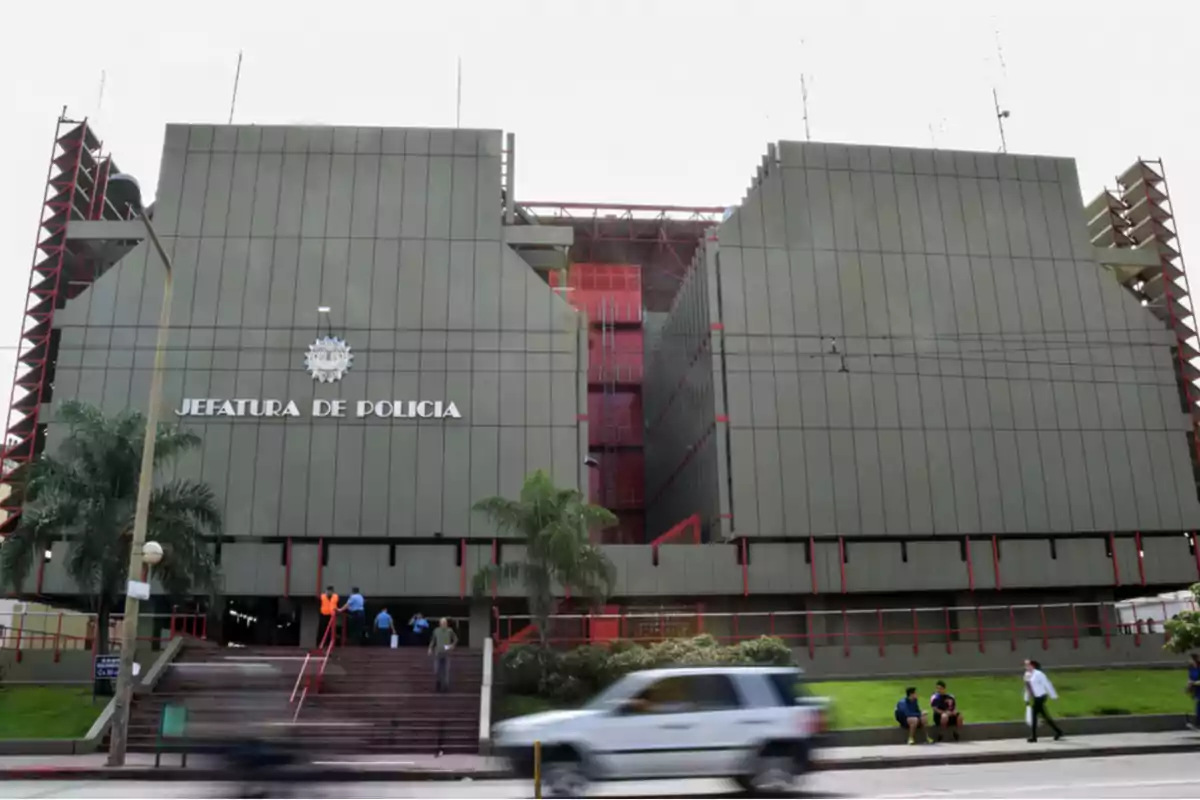Edificio grande de la jefatura de policía con personas entrando y saliendo y autos pasando por la calle frente al edificio Edificio grande de la jefatura de policía con personas entrando y saliendo y autos pasando por la calle frente al edificio