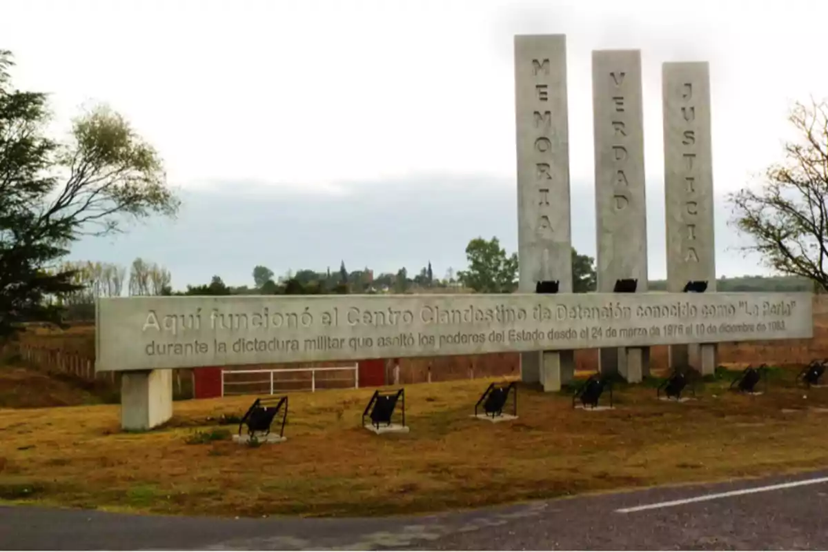 Monumento de hormigón en un espacio abierto con las palabras memoria, verdad y justicia, y una inscripción que recuerda el funcionamiento de un centro clandestino de detención durante la dictadura militar en Argentina