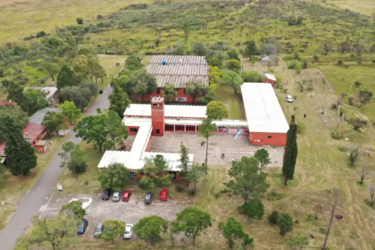 Aerial view of a brick building surrounded by trees and green areas, with a parking lot in front where several cars are parked. Aerial view of a brick building surrounded by trees and green areas, with a parking lot in front where several cars are parked.