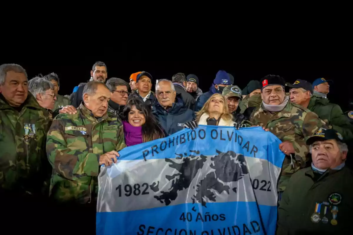 Grupo de personas, en su mayoría veteranos con ropa de camuflaje, sostienen una bandera argentina que conmemora los 40 años de la guerra de Malvinas con la frase Prohibido Olvidar Grupo de personas, en su mayoría veteranos con ropa de camuflaje, sostienen una bandera argentina que conmemora los 40 años de la guerra de Malvinas con la frase Prohibido Olvidar