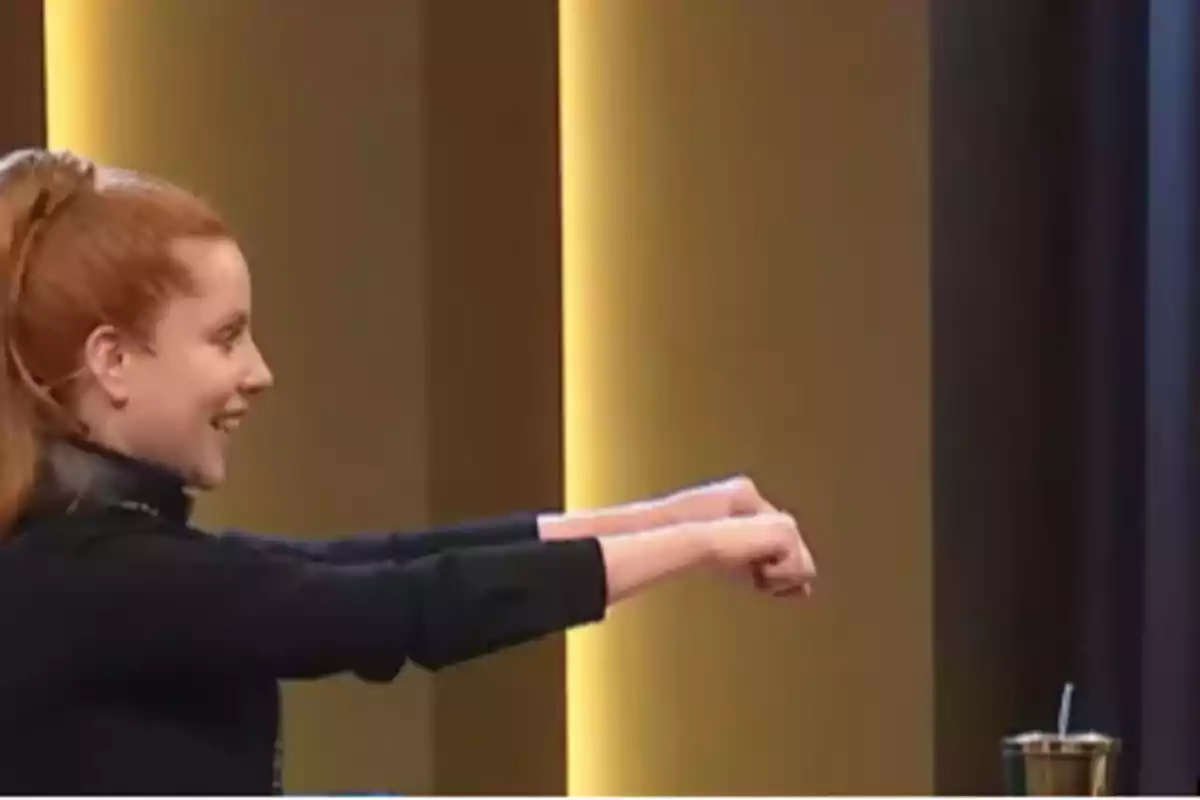 Smiling red-haired woman with her arms extended forward in a brightly lit indoor setting Smiling red-haired woman with her arms extended forward in a brightly lit indoor setting