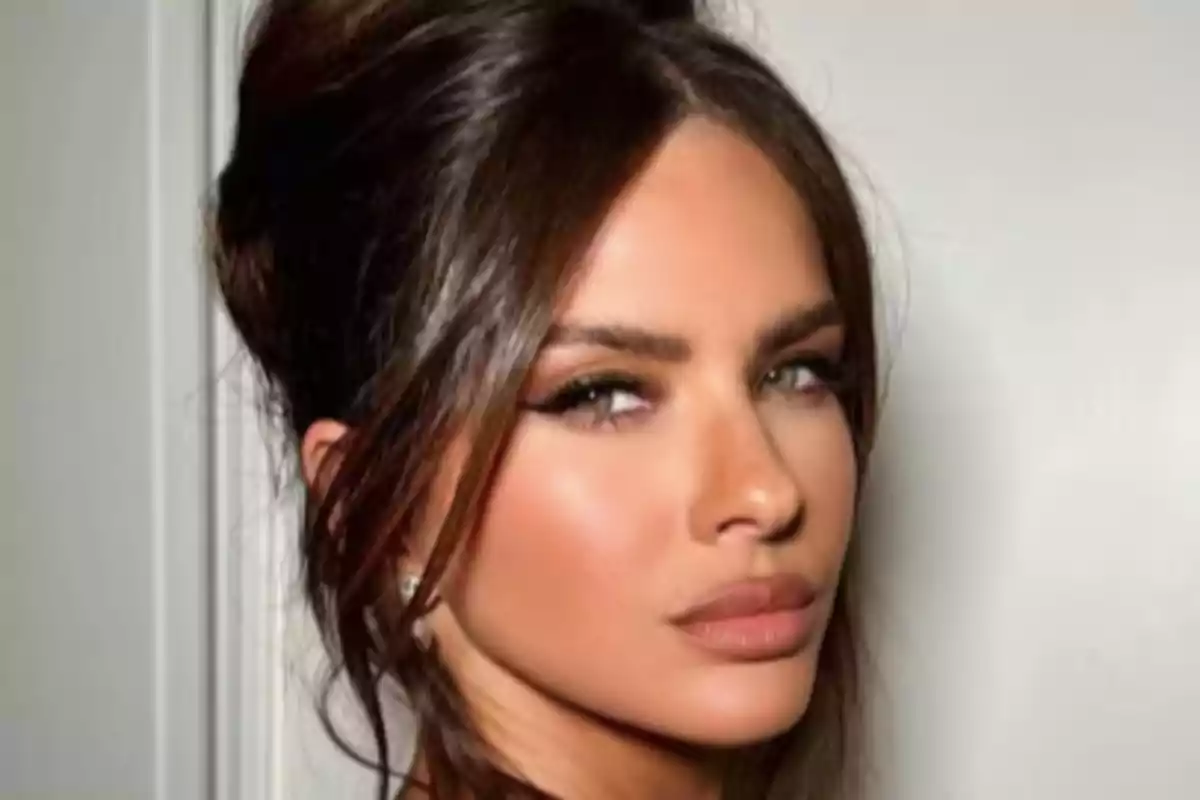 Mujer de cabello castaño recogido con maquillaje elegante y expresión seria