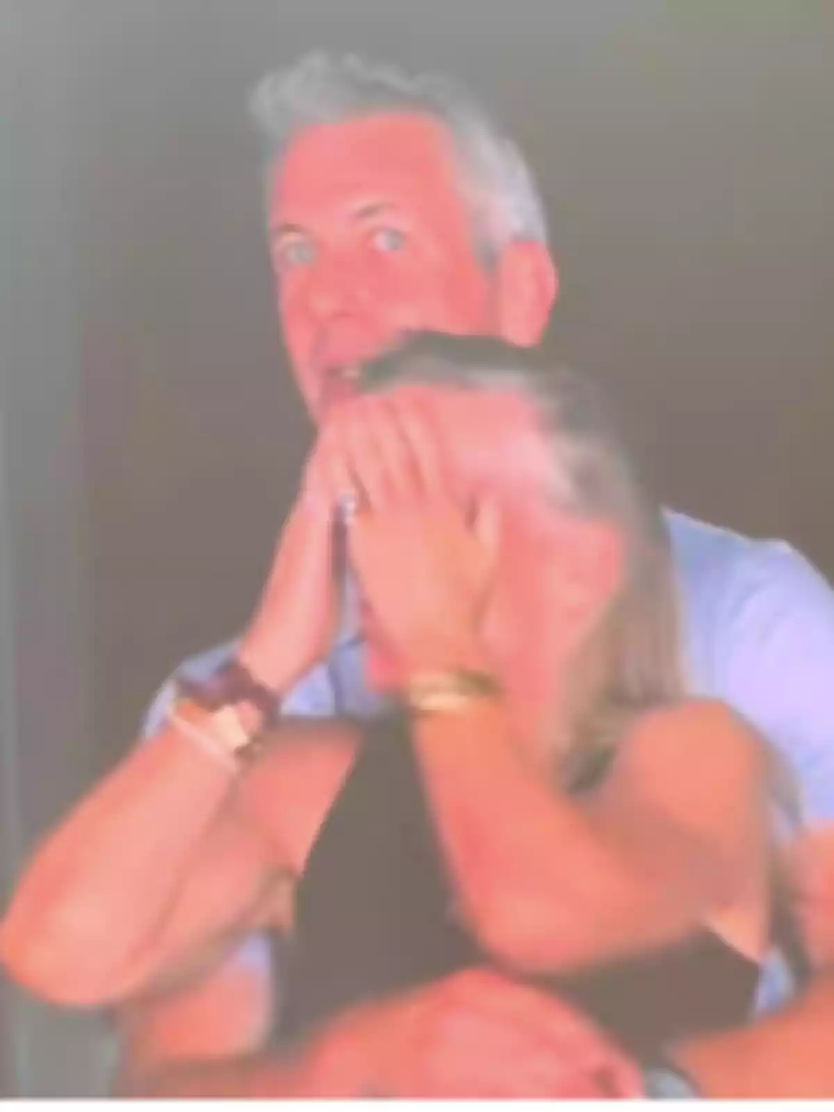 A man hugs a woman who covers her face with her hands in a blurred image. A man hugs a woman who covers her face with her hands in a blurred image.