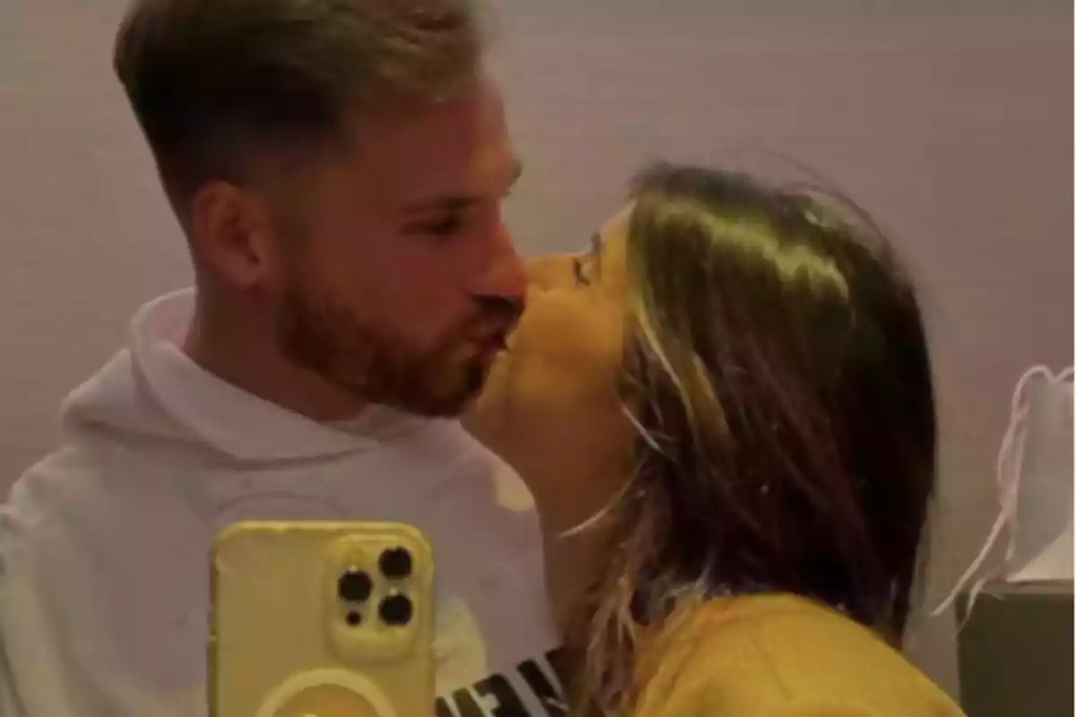 Pareja tomándose una selfie mientras se dan un beso Pareja tomándose una selfie mientras se dan un beso