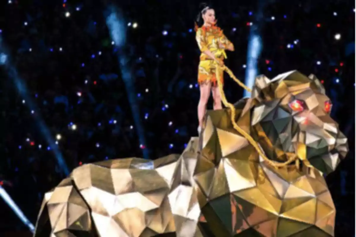 Woman dressed in yellow riding a giant golden lion figure on a lit stage Woman dressed in yellow riding a giant golden lion figure on a lit stage