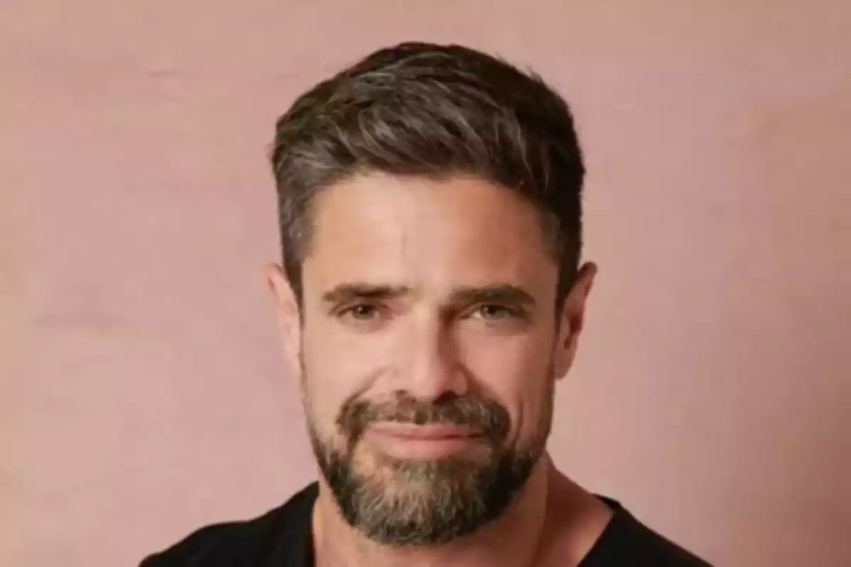 Short-haired, bearded man with a friendly expression in front of a light pink background