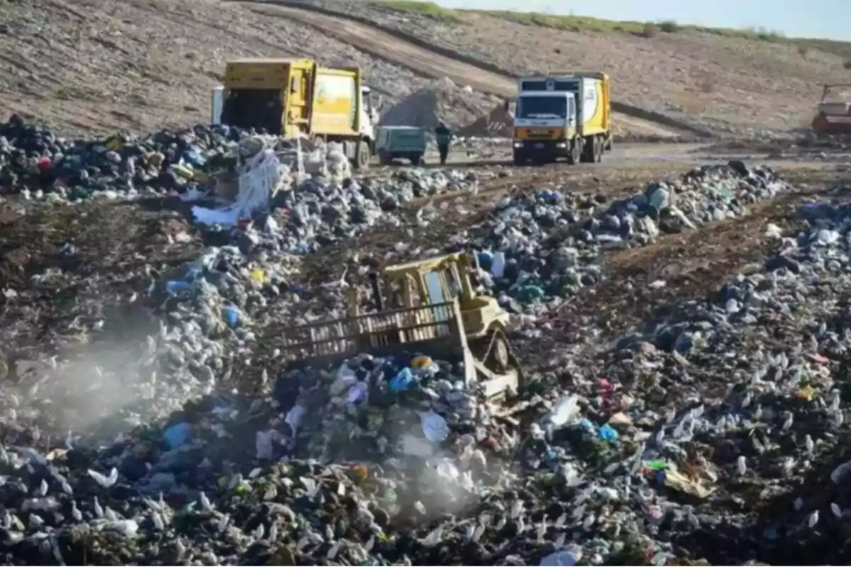 Camiones de basura y maquinaria trabajando en un vertedero lleno de residuos sólidos Camiones de basura y maquinaria trabajando en un vertedero lleno de residuos sólidos