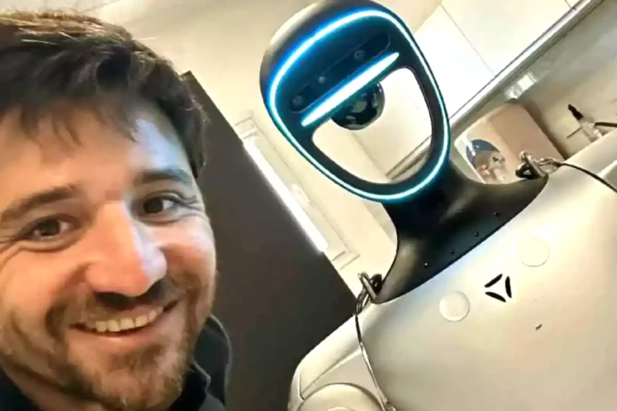 Hombre sonriente tomándose una selfie junto a un robot en un entorno interior moderno