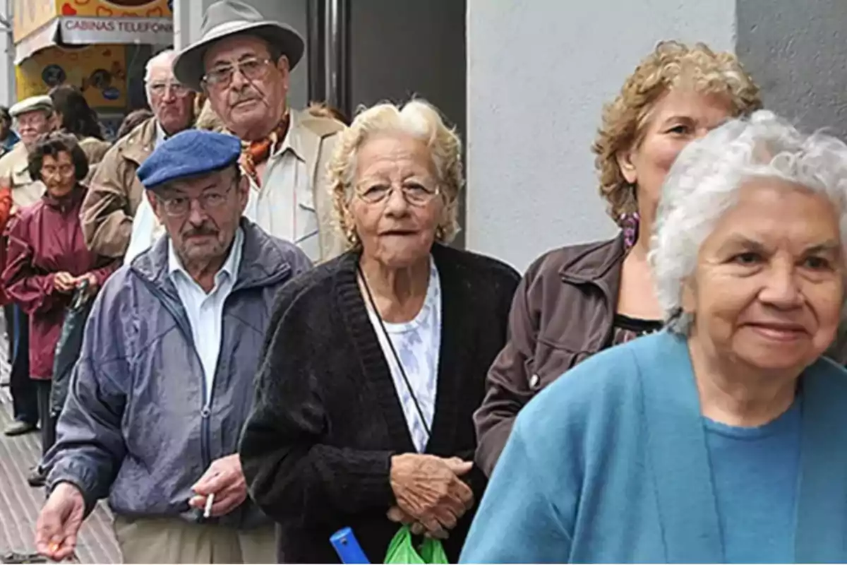 Personas mayores haciendo fila en la calle frente a un edificio