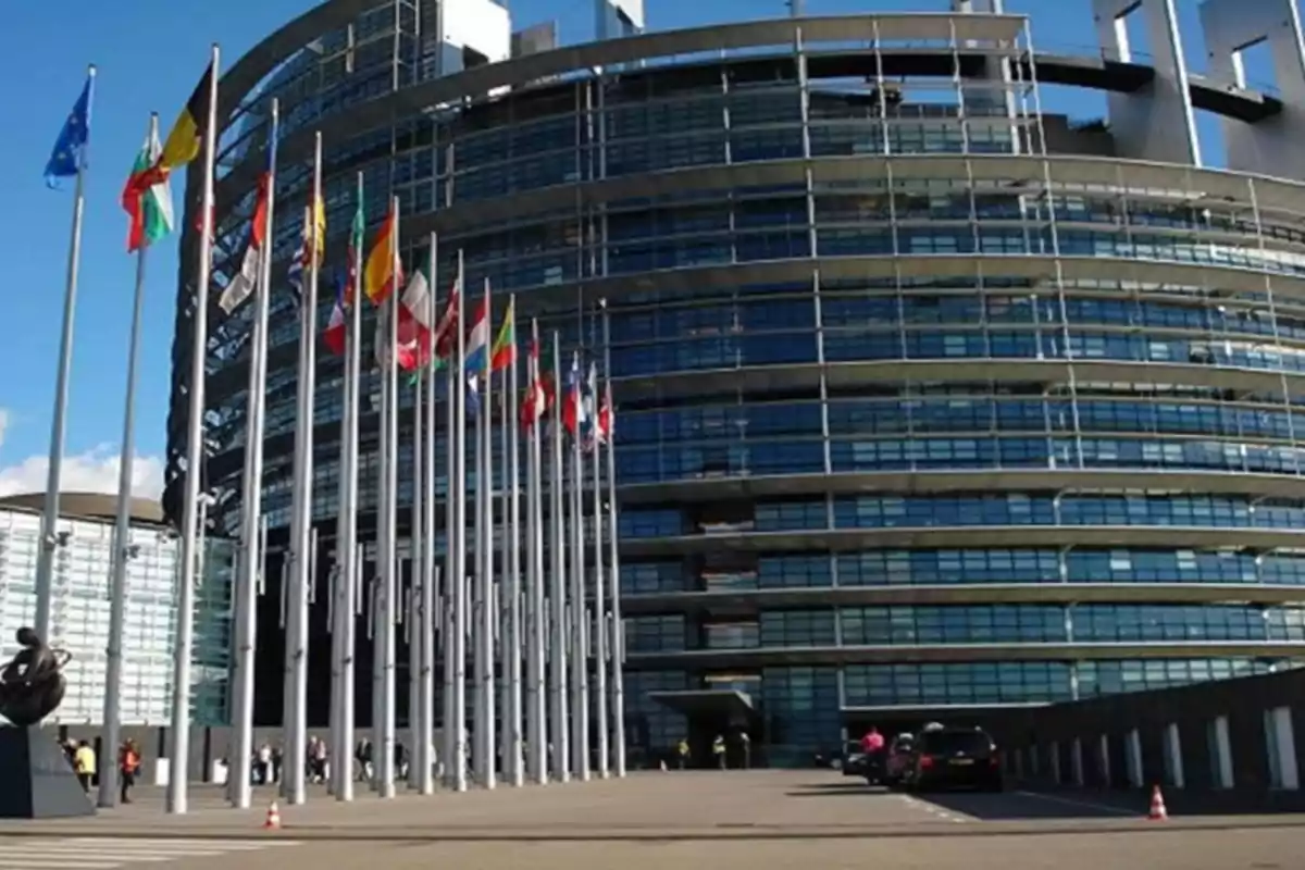 Edificio moderno de vidrio con varias banderas de diferentes países alineadas en la entrada