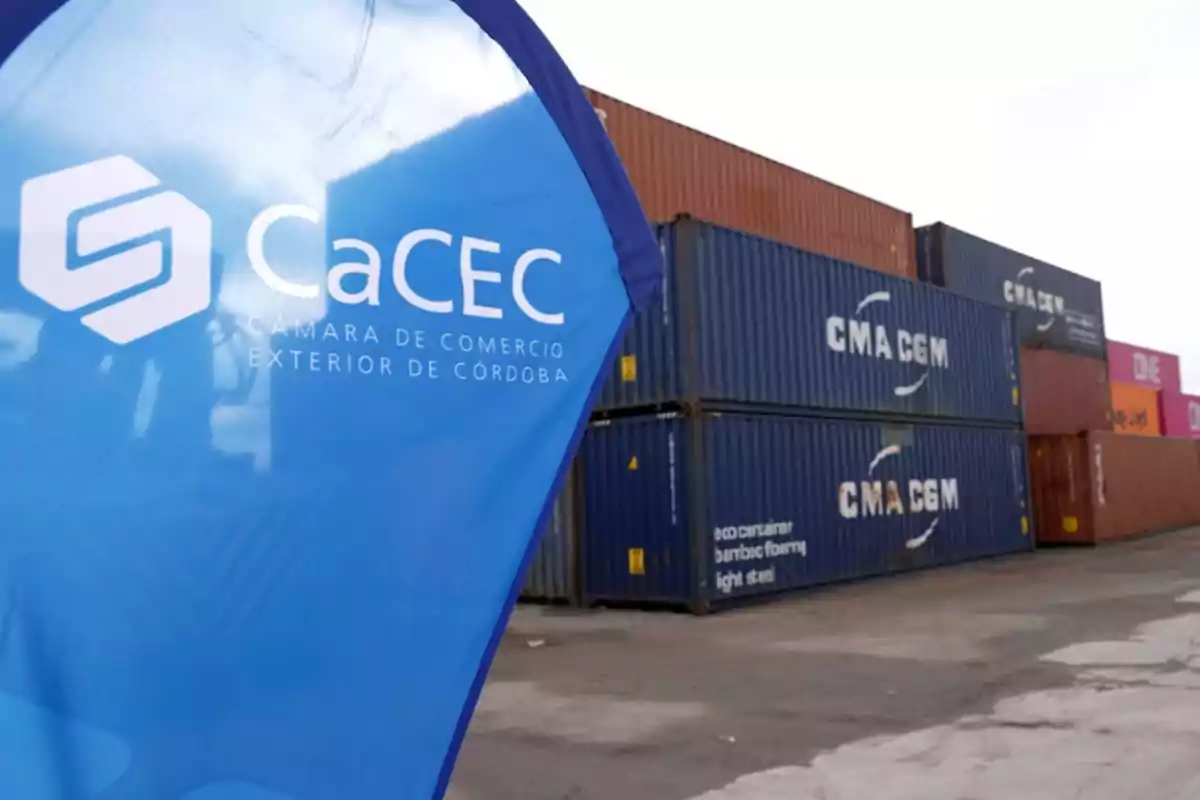 Banner azul de la Cámara de Comercio Exterior de Córdoba junto a varios contenedores apilados en un puerto o depósito industrial