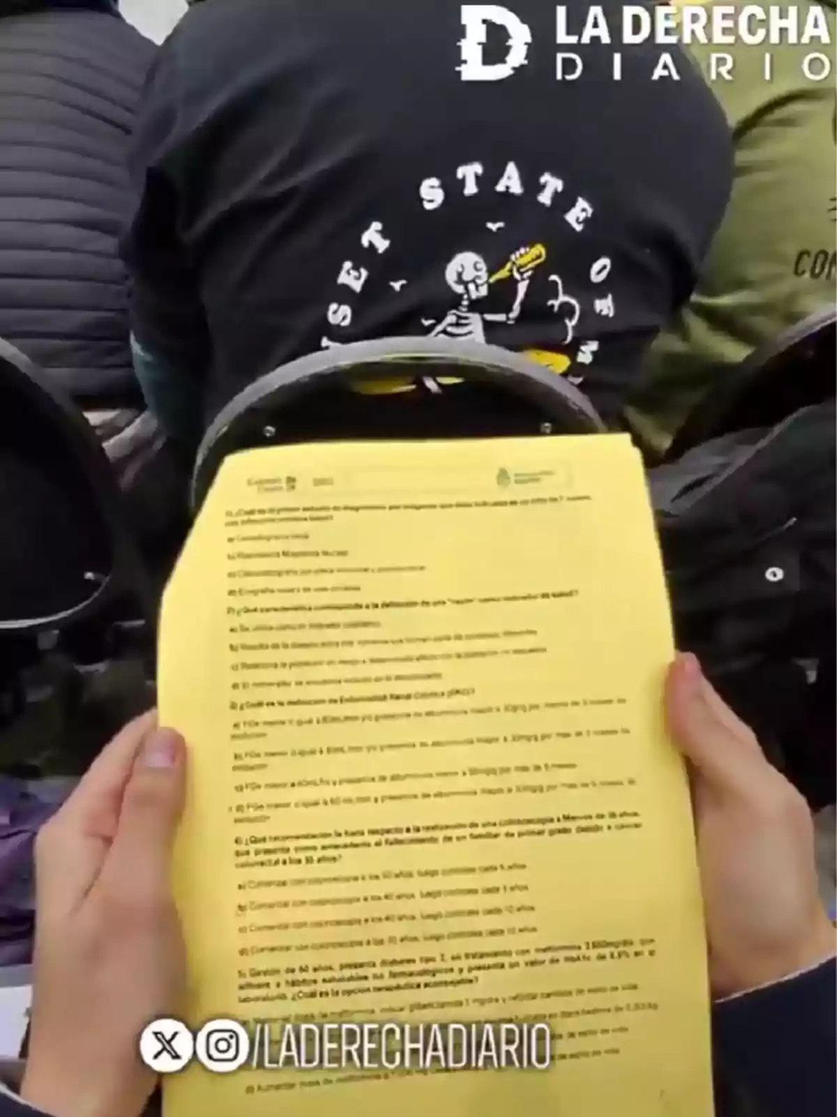 Persona sosteniendo una hoja amarilla con preguntas impresas mientras está sentada detrás de otras personas en un auditorio, con el logo de La Derecha Diario en la esquina superior derecha Persona sosteniendo una hoja amarilla con preguntas impresas mientras está sentada detrás de otras personas en un auditorio, con el logo de La Derecha Diario en la esquina superior derecha
