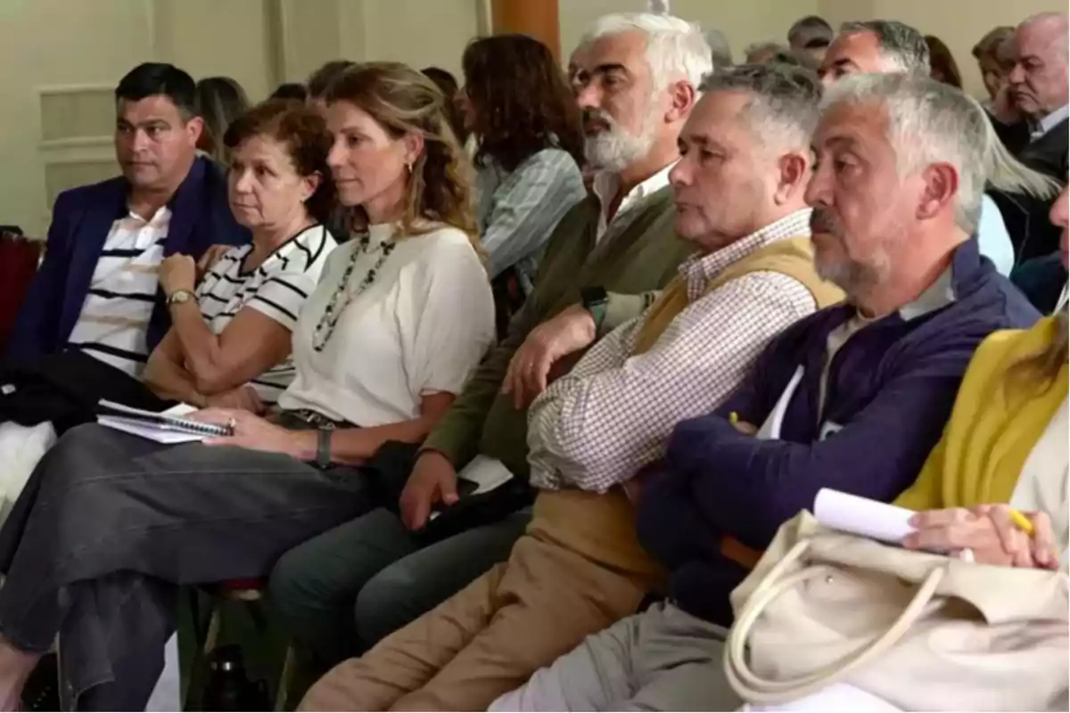 Adults sitting in a room paying attention to a presentation or lecture, some with notebooks and pens in their hands. Adults sitting in a room paying attention to a presentation or lecture, some with notebooks and pens in their hands.
