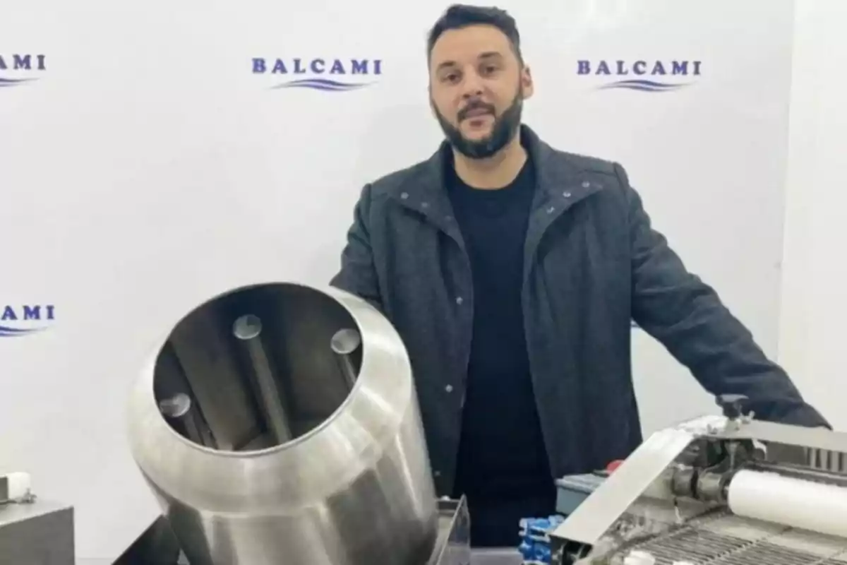 Man standing next to a stainless steel industrial machine with the Balcami logo on the wall in the background