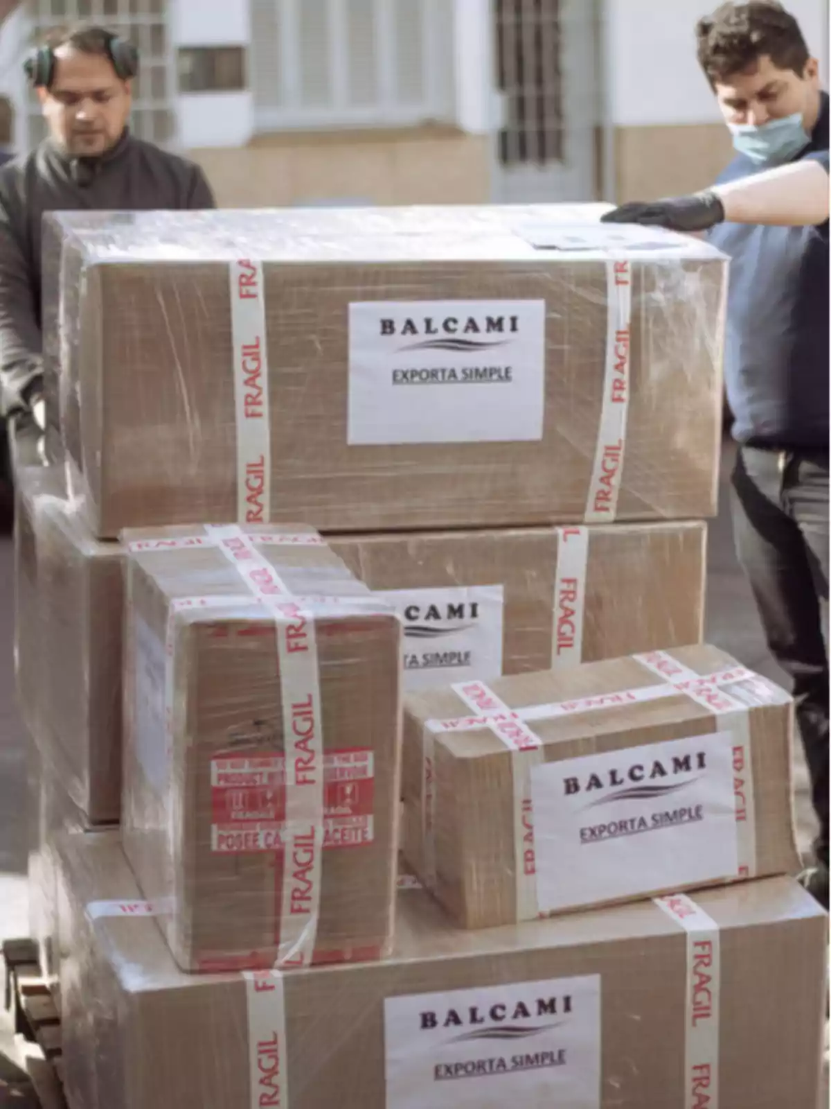 Several packages wrapped with fragile tape and simple export labels from the company BALCAMI being handled by two people Several packages wrapped with fragile tape and simple export labels from the company BALCAMI being handled by two people