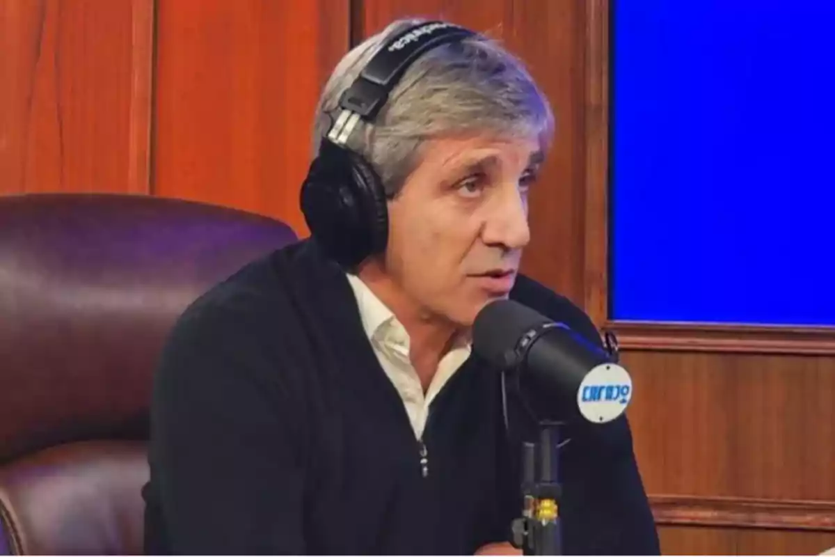 Hombre de cabello canoso usando audífonos y hablando frente a un micrófono en un estudio de radio con fondo de madera y pantalla azul Hombre de cabello canoso usando audífonos y hablando frente a un micrófono en un estudio de radio con fondo de madera y pantalla azul