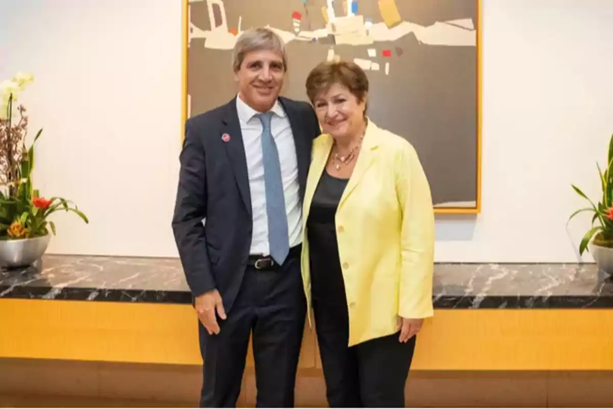 Dos personas posan sonrientes frente a una mesa de mármol negro con plantas a los costados y un cuadro abstracto en la pared.