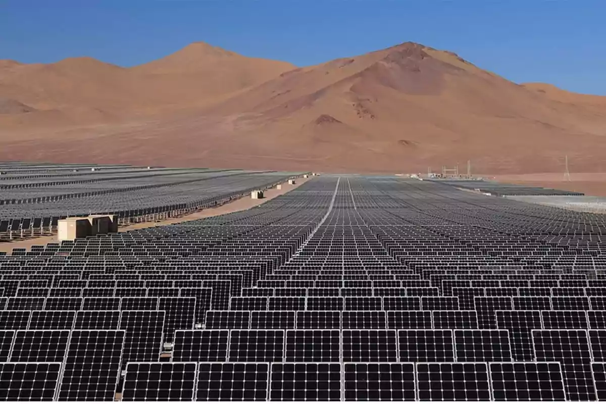 Large field of solar panels in the desert with mountains in the background and clear sky