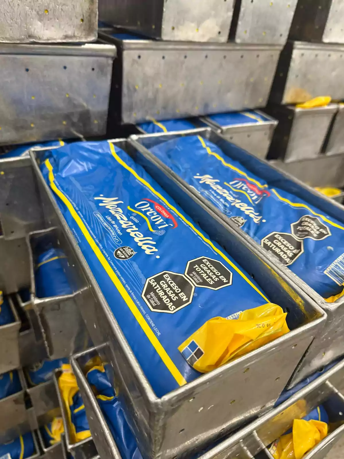 Bloques de queso mozzarella empacados en bolsas azules y colocados dentro de moldes metálicos rectangulares Bloques de queso mozzarella empacados en bolsas azules y colocados dentro de moldes metálicos rectangulares