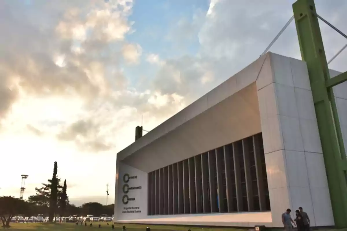 Modern building of the Córdoba Convention Center with a white structure and green details at sunset, partly cloudy sky, and people at the entrance Modern building of the Córdoba Convention Center with a white structure and green details at sunset, partly cloudy sky, and people at the entrance