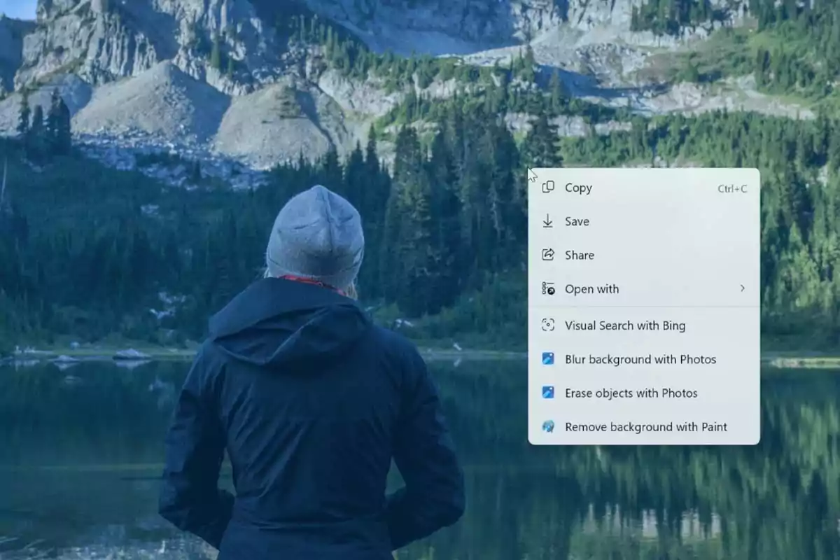 Person seen from behind wearing a gray beanie and dark jacket, looking at a lake surrounded by trees and mountains, while a floating digital editing options menu appears in the image. Person seen from behind wearing a gray beanie and dark jacket, looking at a lake surrounded by trees and mountains, while a floating digital editing options menu appears in the image.