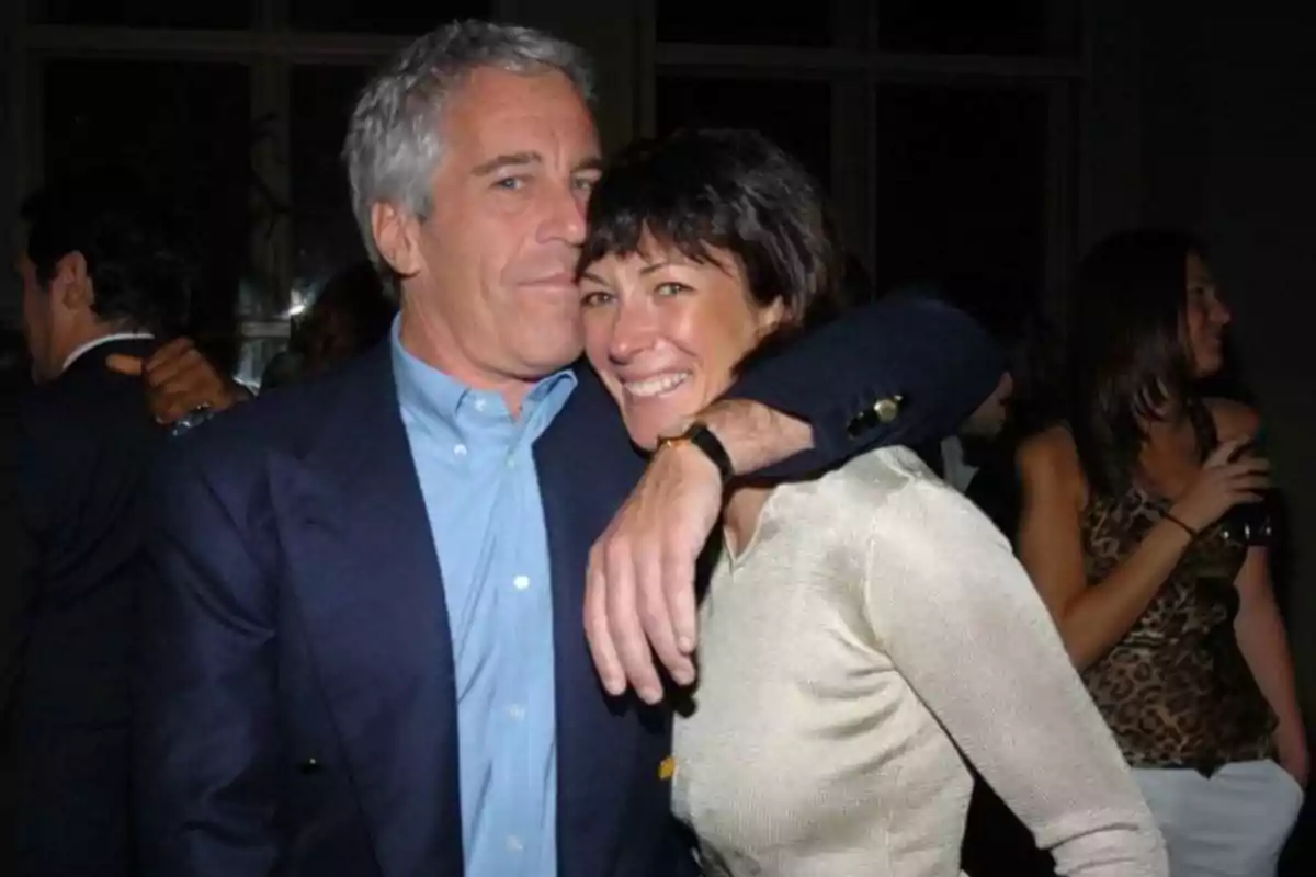 A gray-haired man hugs a dark-haired woman while both smile at what appears to be a party or social gathering. A gray-haired man hugs a dark-haired woman while both smile at what appears to be a party or social gathering.