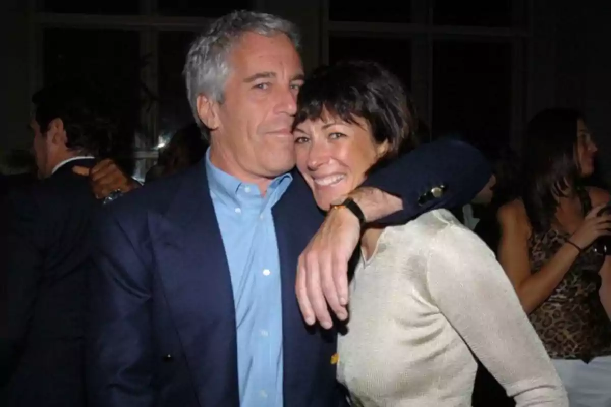 Dos personas abrazadas y sonriendo en una fiesta con otras personas al fondo Dos personas abrazadas y sonriendo en una fiesta con otras personas al fondo