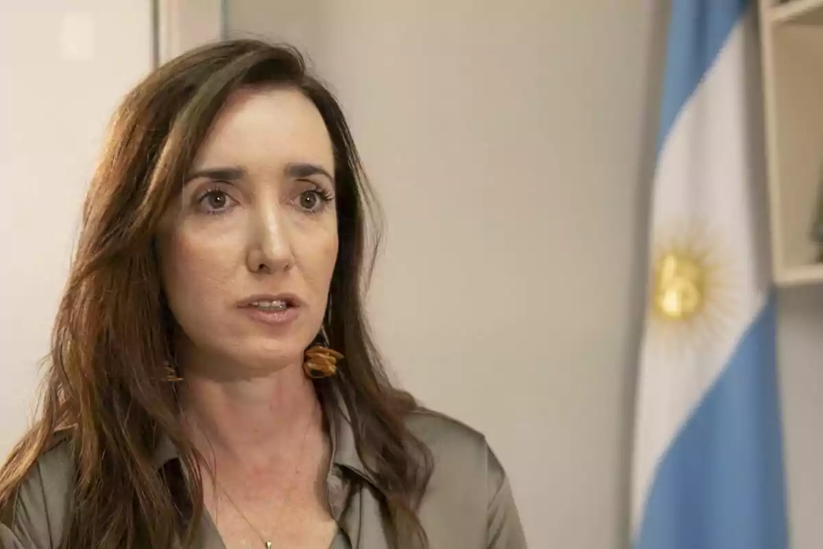 Long-haired brunette woman with a serious expression and an Argentine flag in the background Long-haired brunette woman with a serious expression and an Argentine flag in the background