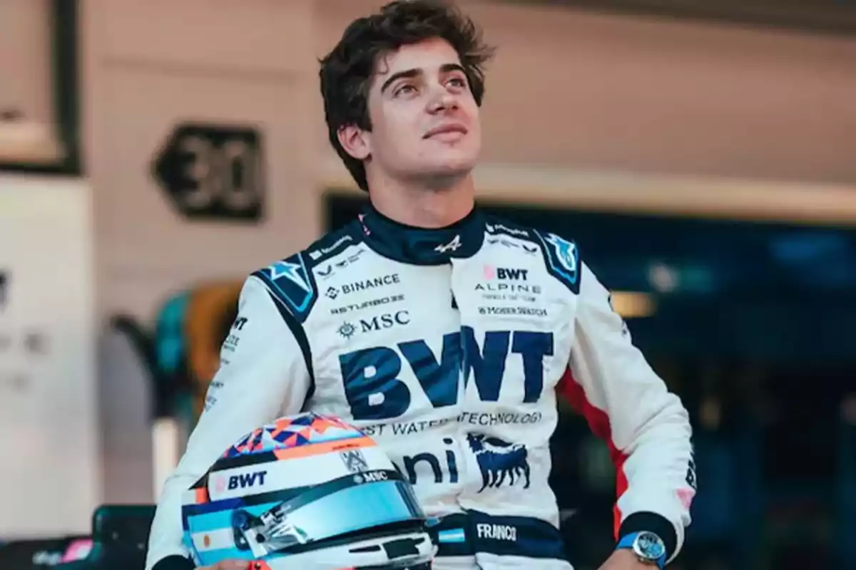 Motorsport driver in a white and blue racing suit holding a helmet in front of a pit garage Motorsport driver in a white and blue racing suit holding a helmet in front of a pit garage