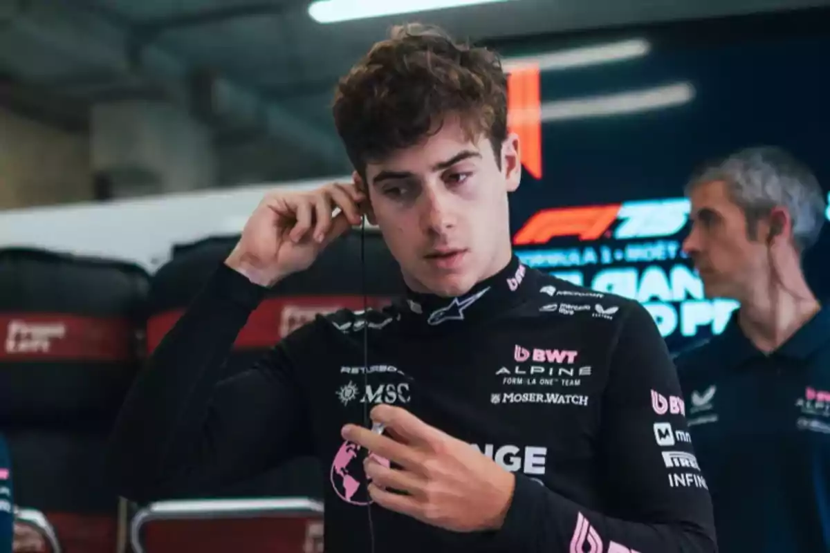 Joven piloto de automovilismo con uniforme negro de Alpine preparándose en el paddock antes de una carrera de Fórmula 1