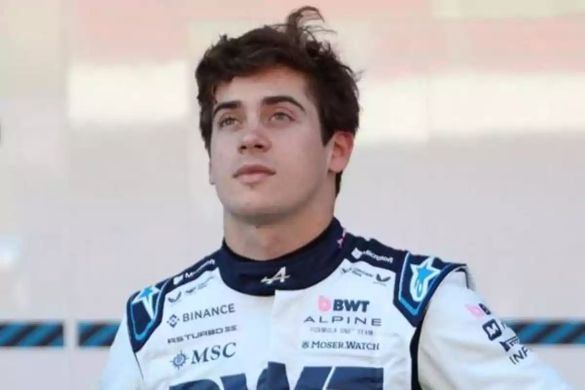 Young race car driver in a white and blue racing suit looking up