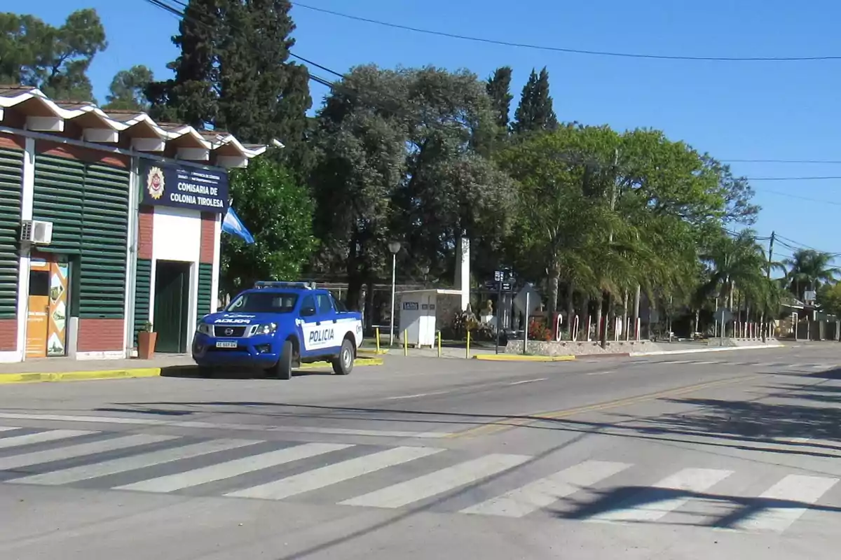 Police patrol car parked in front of a police station on a quiet street with trees and a crosswalk