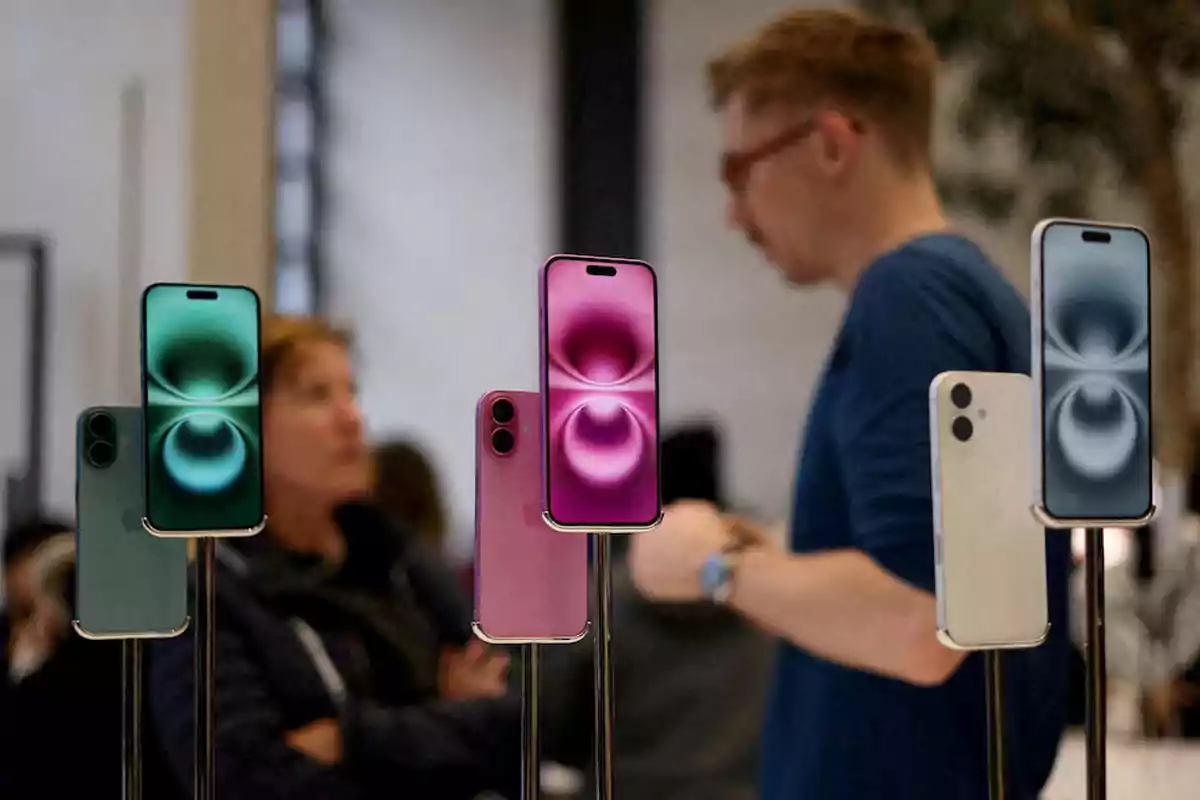 Varios teléfonos inteligentes de diferentes colores exhibidos en una tienda con personas desenfocadas al fondo Varios teléfonos inteligentes de diferentes colores exhibidos en una tienda con personas desenfocadas al fondo