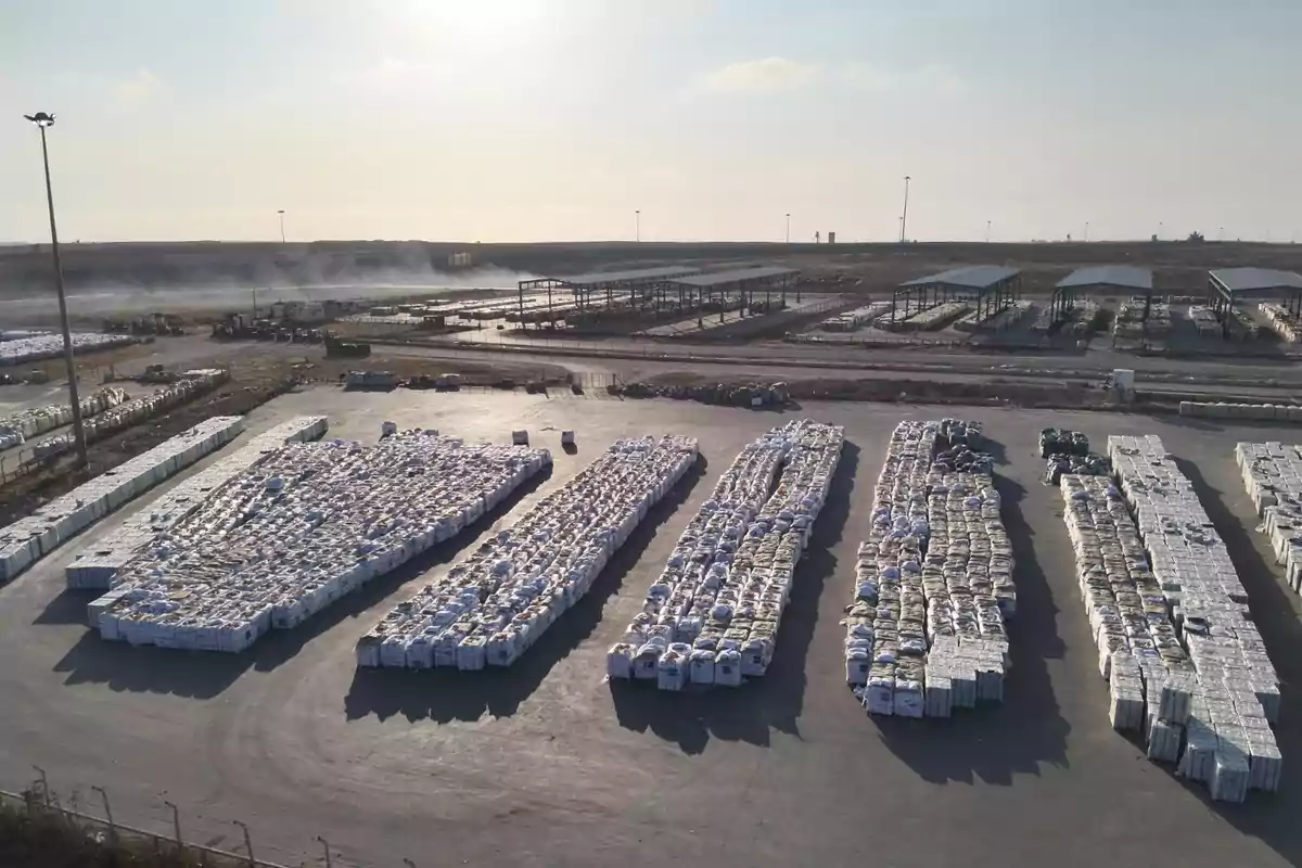 Vista aérea de un almacén industrial con grandes filas de materiales apilados y estructuras metálicas al fondo