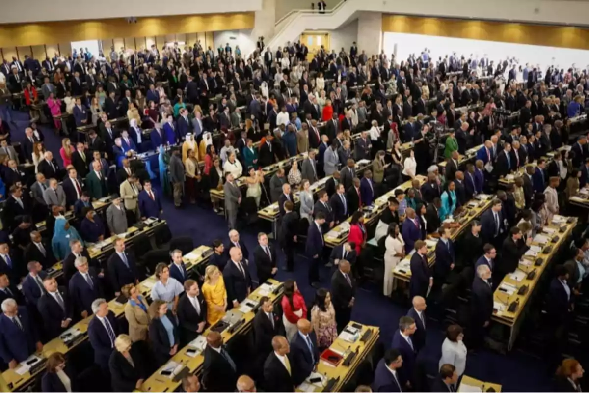 Large number of people standing in an auditorium during a formal event Large number of people standing in an auditorium during a formal event