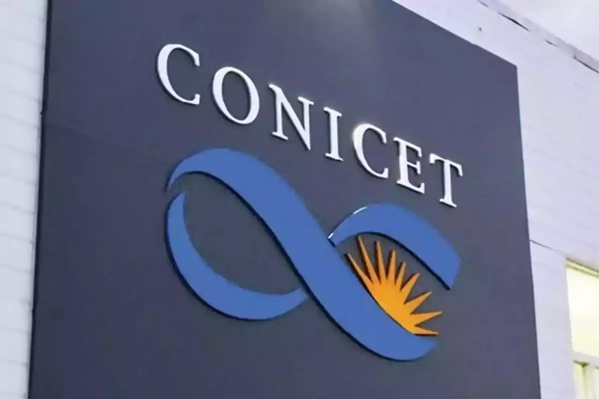 Cartel de CONICET con el logo azul y amarillo en la fachada de un edificio Cartel de CONICET con el logo azul y amarillo en la fachada de un edificio