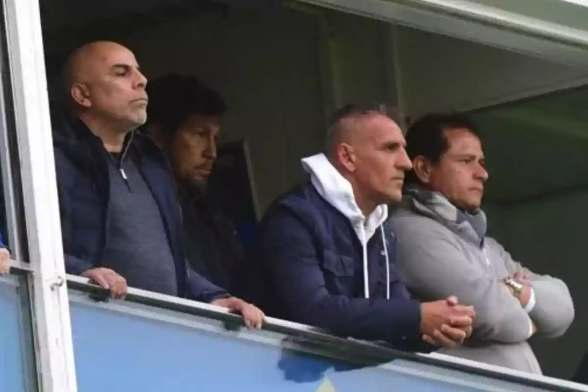 Cuatro hombres observan atentamente un partido desde un palco en un estadio. Cuatro hombres observan atentamente un partido desde un palco en un estadio.