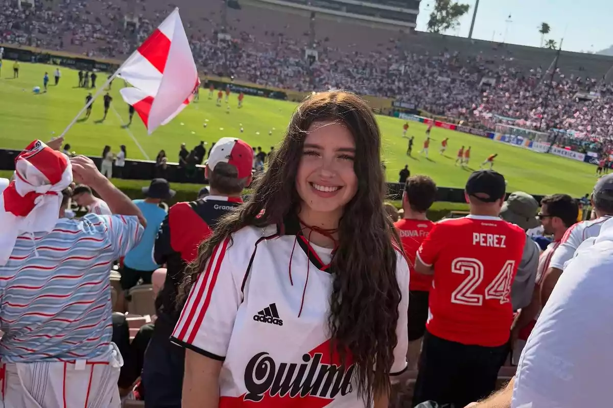 Joven sonriente con camiseta de River Plate en un estadio lleno durante un partido de fútbol Joven sonriente con camiseta de River Plate en un estadio lleno durante un partido de fútbol