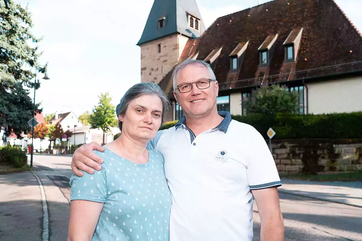 Pareja de mediana edad posando junta en una calle tranquila con casas y árboles al fondo Pareja de mediana edad posando junta en una calle tranquila con casas y árboles al fondo