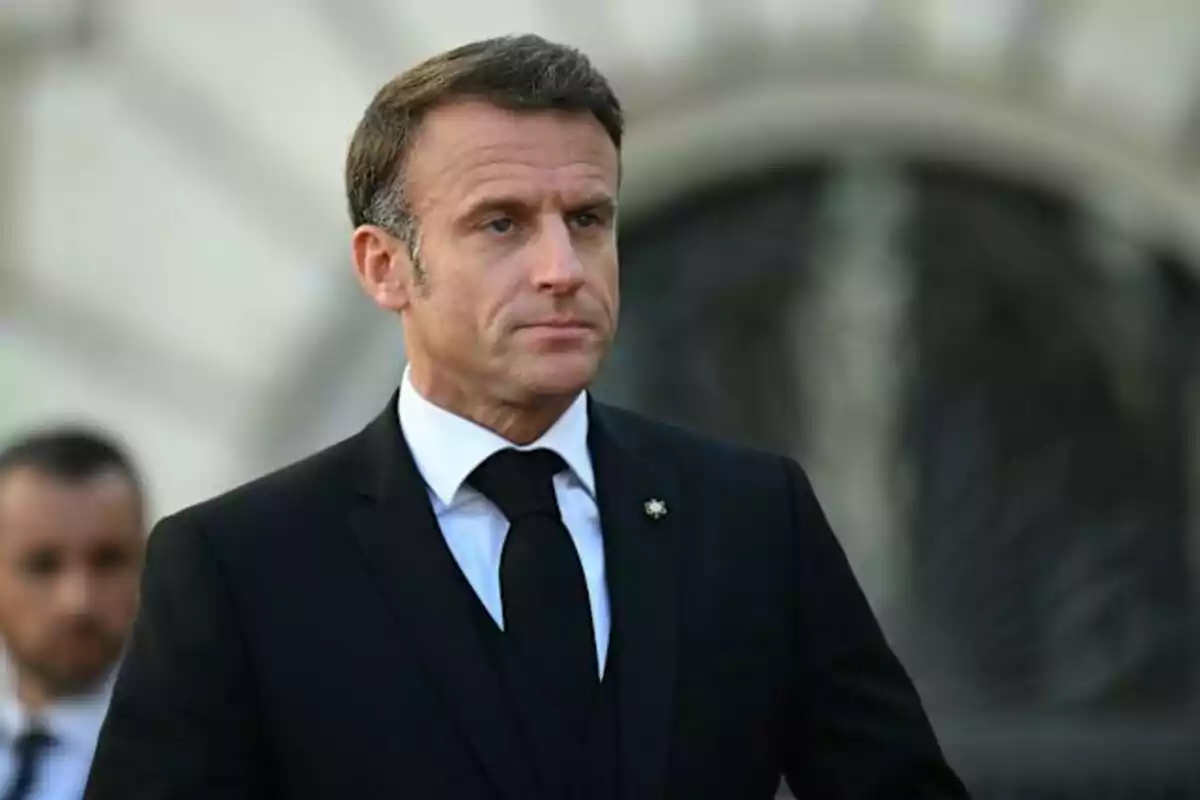 Hombre de cabello corto y traje negro con corbata negra en un entorno exterior formal Hombre de cabello corto y traje negro con corbata negra en un entorno exterior formal