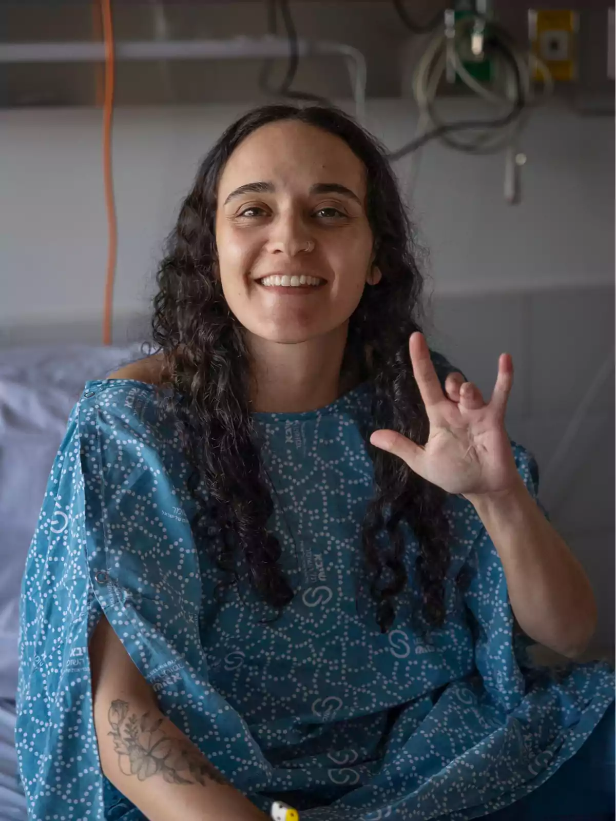 Woman in a hospital gown smiles and makes the Woman in a hospital gown smiles and makes the